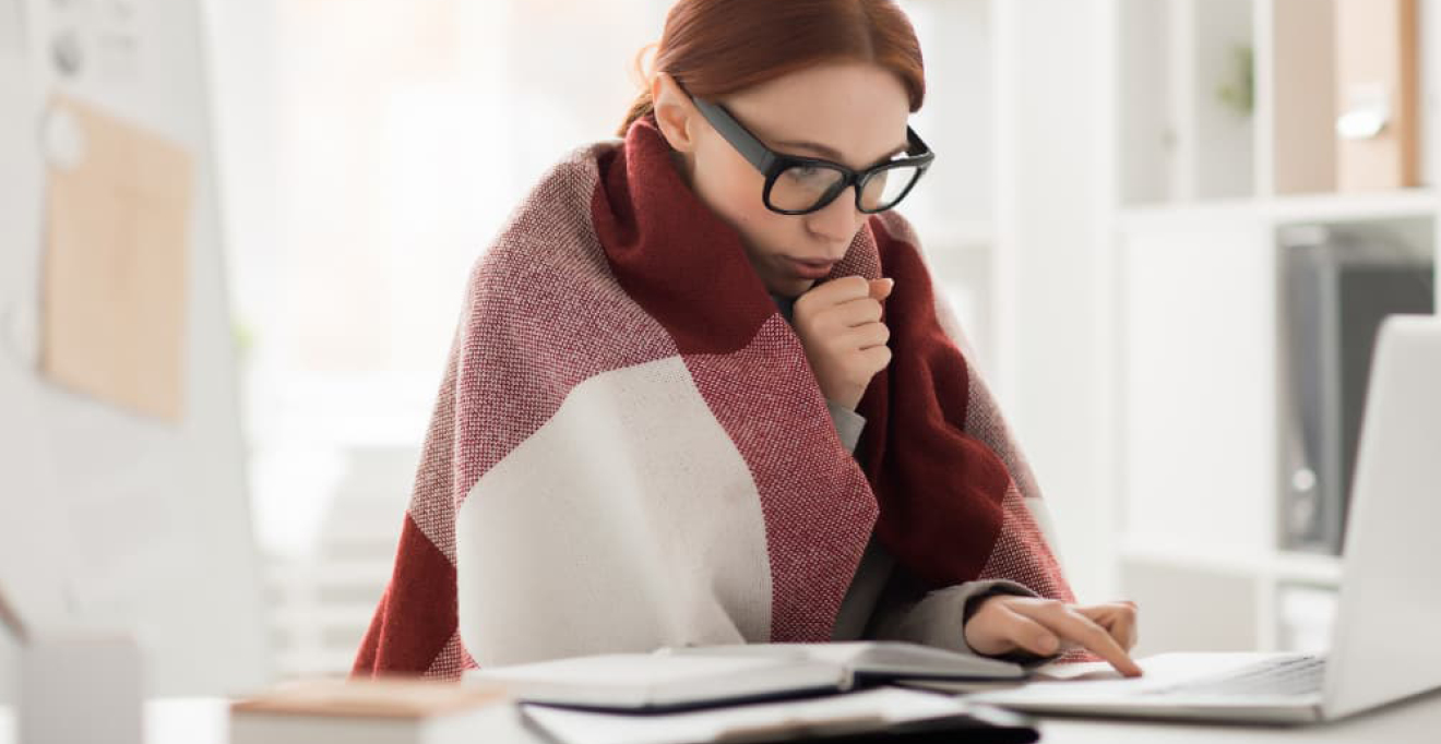 Woman wrapped in a blanket while working at her desk