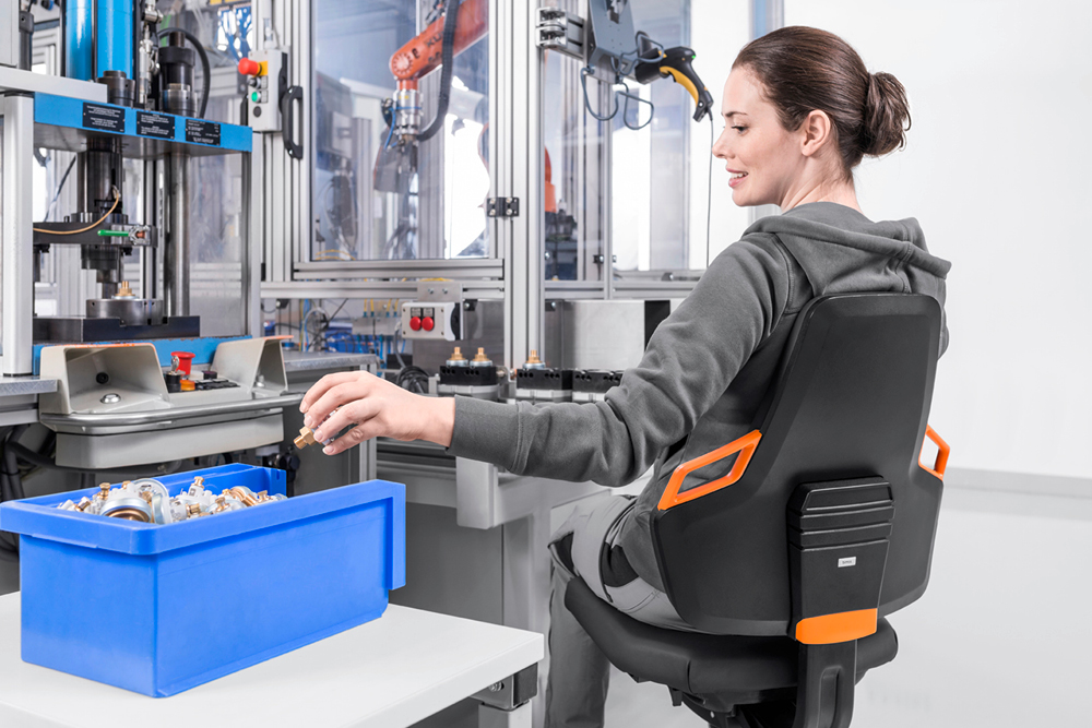 Woman working in an industrial environment sitting in an ergonomic chair