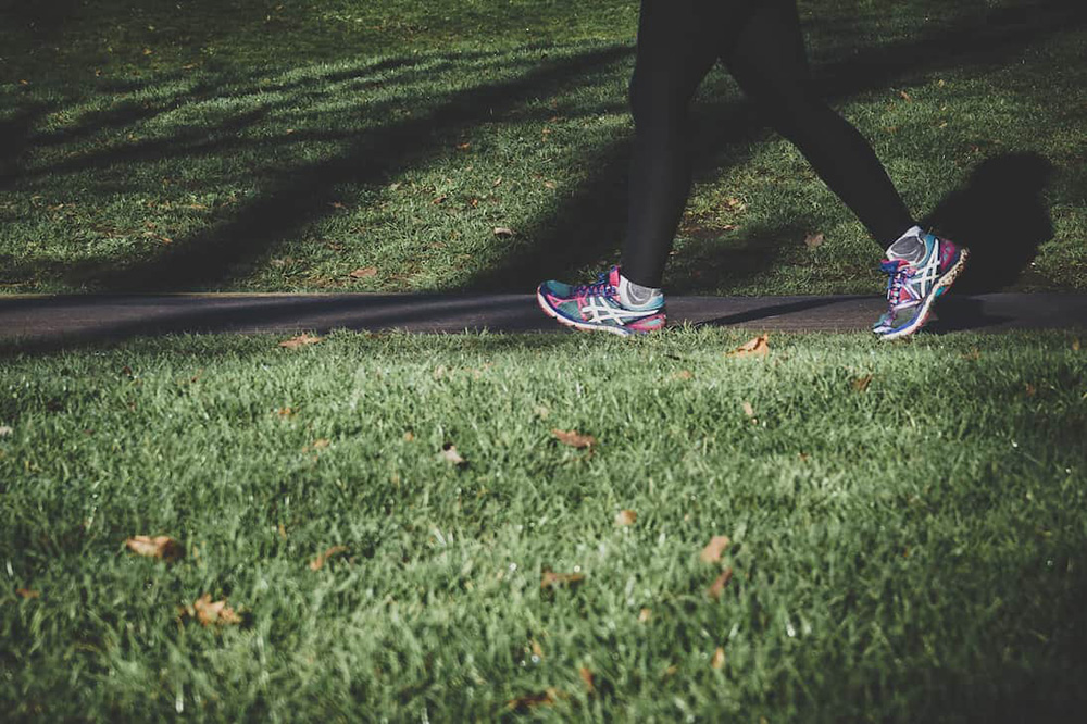 Close up of a woman's running shoes as she jogs through a park