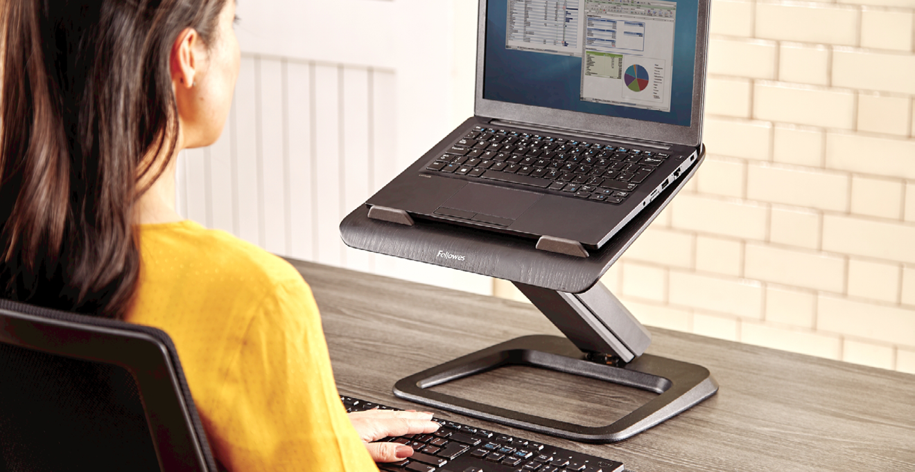 Woman in yellow jumper using laptop with a stand