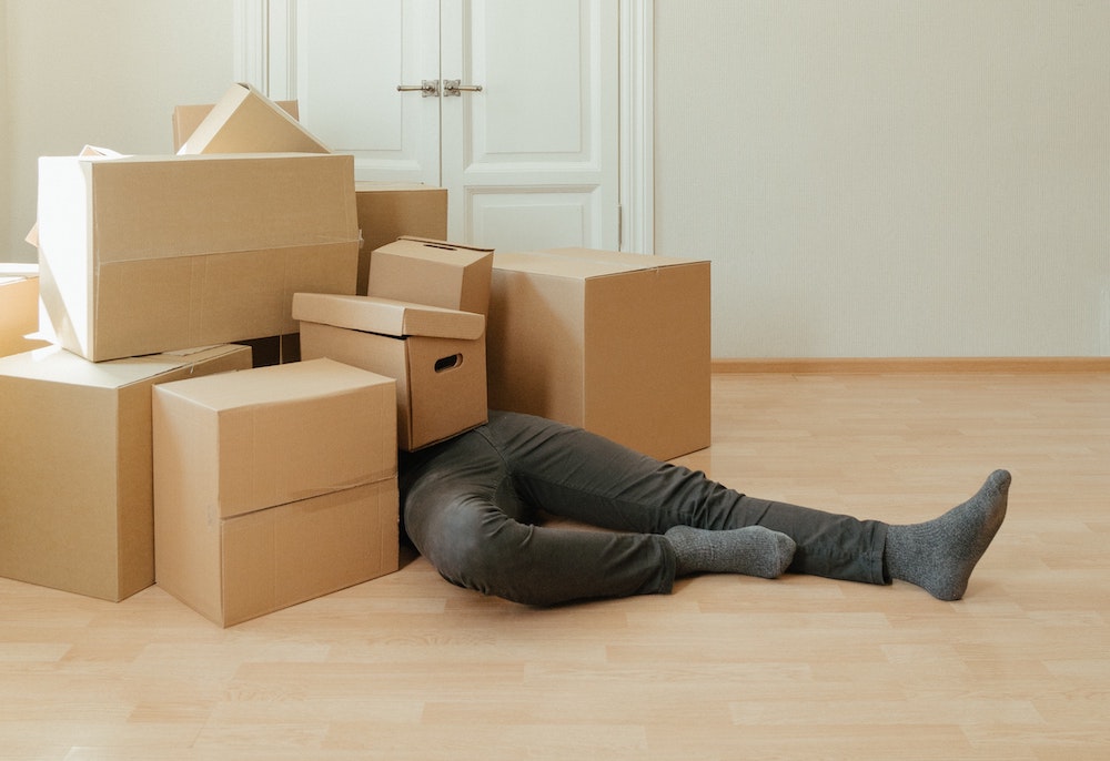 Man lying underneath some cardboard boxes after a fall
