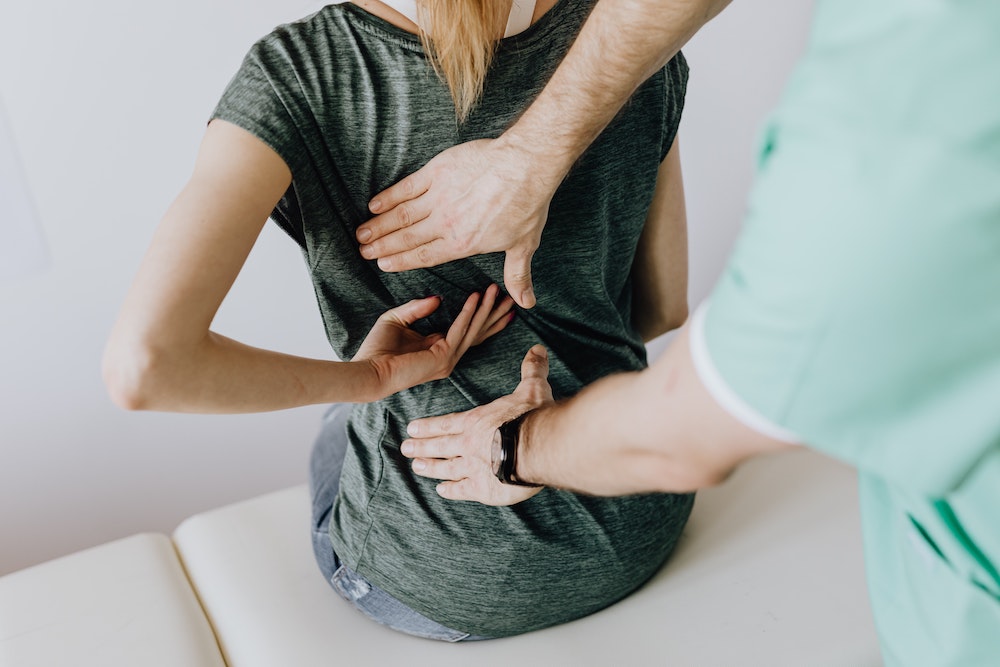 Woman with back pain, being assessed by a medical expert