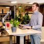 JOSHO Homeworker Beech Electric Sit-Stand Desk - lifestyle shot close up, shown raised in the standing position