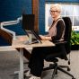 KOJI Italian Oak Electric Sit-Stand Desk - lifestyle shot, shown lowered in the seated position