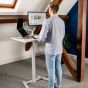 KOJI White Electric Sit-Stand Desk - lifestyle shot, shown raised in standing position