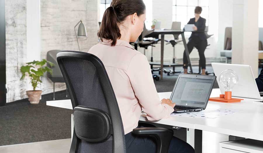 Woman sitting at her desk in a HÅG SoFi mesh back chair
