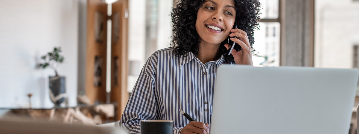 Woman talking on the phone while looking at her laptop