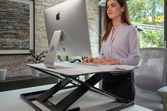 Image of woman working on computer with raised Oploft Sit-Stand Platform  