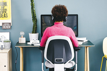 Woman working at her home working desk while sitting on a RH Mereo 220 chair