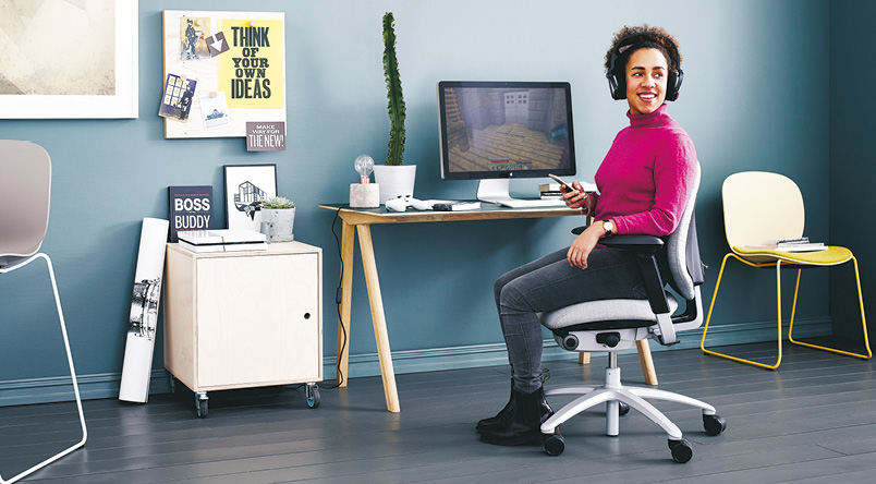 Woman sitting on a RH Mereo 220 chair while working at her home office desk