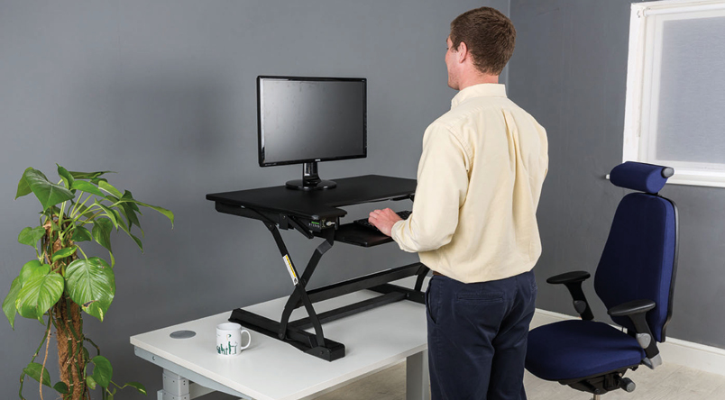Image of a person standing using the DeskRite 100 Sit-Stand Platform