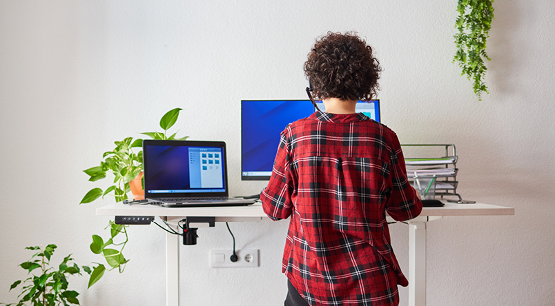 Image of a woman standing using the Josho Electric Sit-Stand Desk