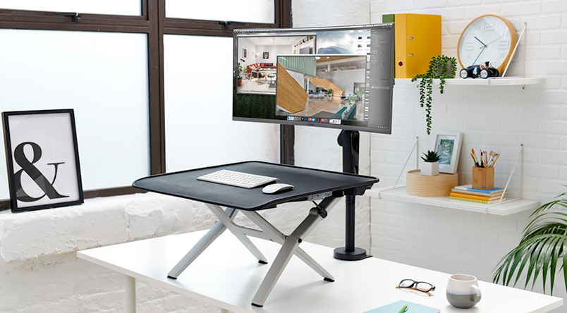 Monto Sit-Stand Riser in the raised position, along with an Ollin Monitor Arm with the extended height desk clamp