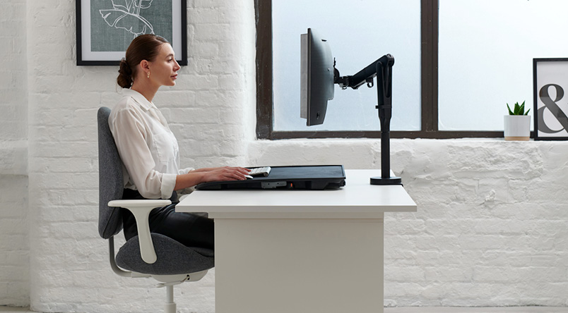 Woman working at her desk, using the Monto Sit-Stand Riser
