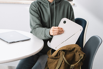 Image of person placing folded version of Oripura Laptop Stand into their backpack