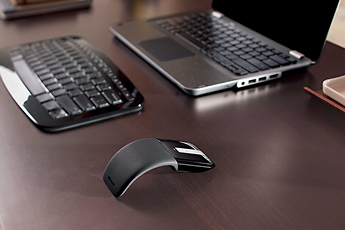 Image showing Microsoft Arc Touch Mouse curved on desk with office set-up