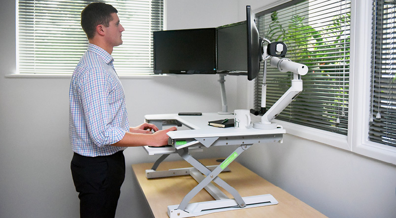 Image of a person standing using the DeskRite 100 Sit-Stand Platform