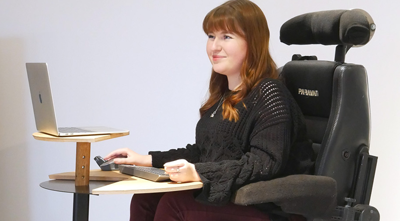 A lady using the Otto Laptop Table with a laptop, separate keyboard and mouse, ensuring a good ergonomic posture