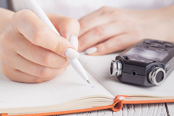 Close up of someone taking notes with a dictaphone